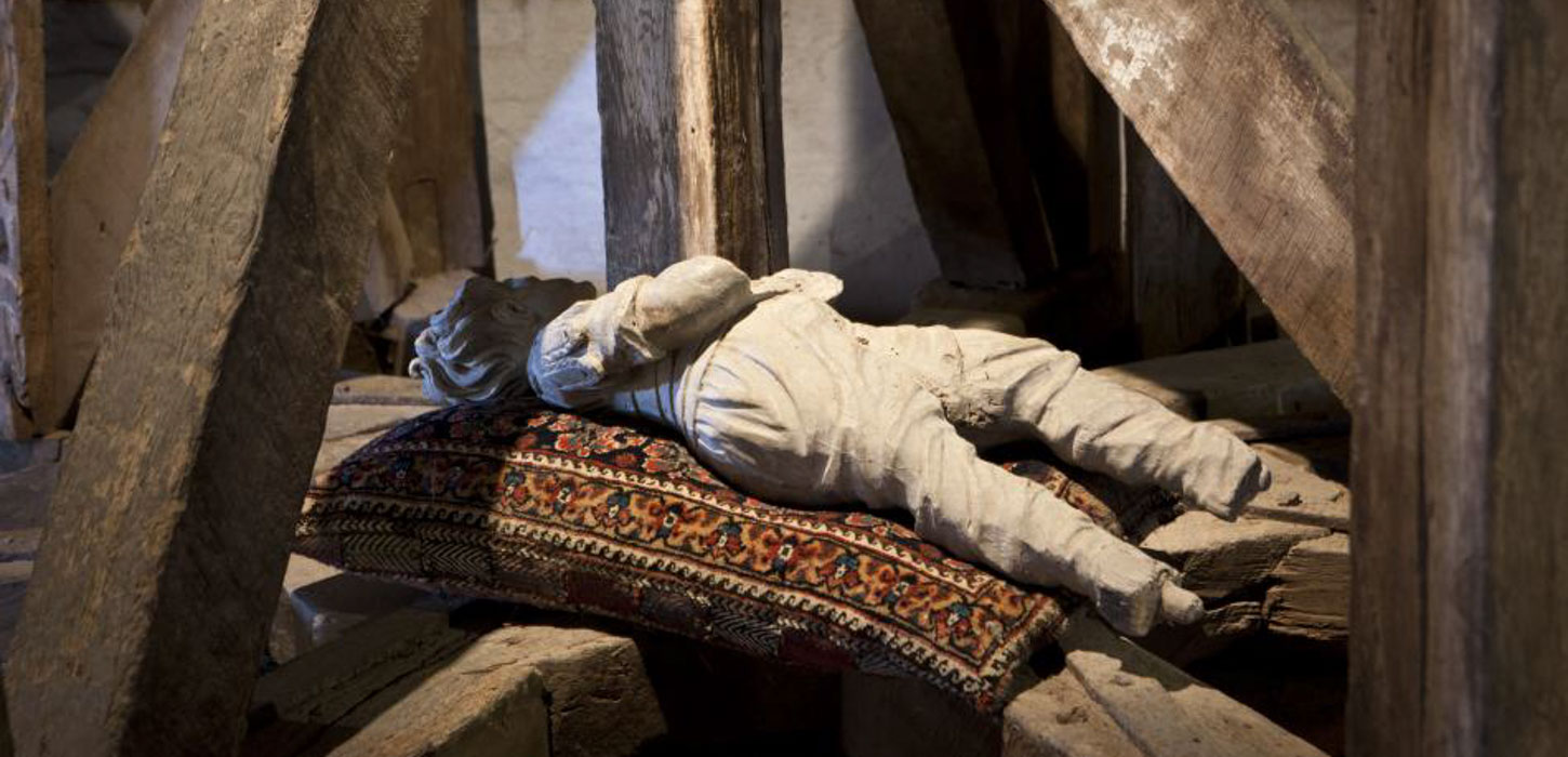 En trædukke ligger på en pude under nogle skrå bjælker