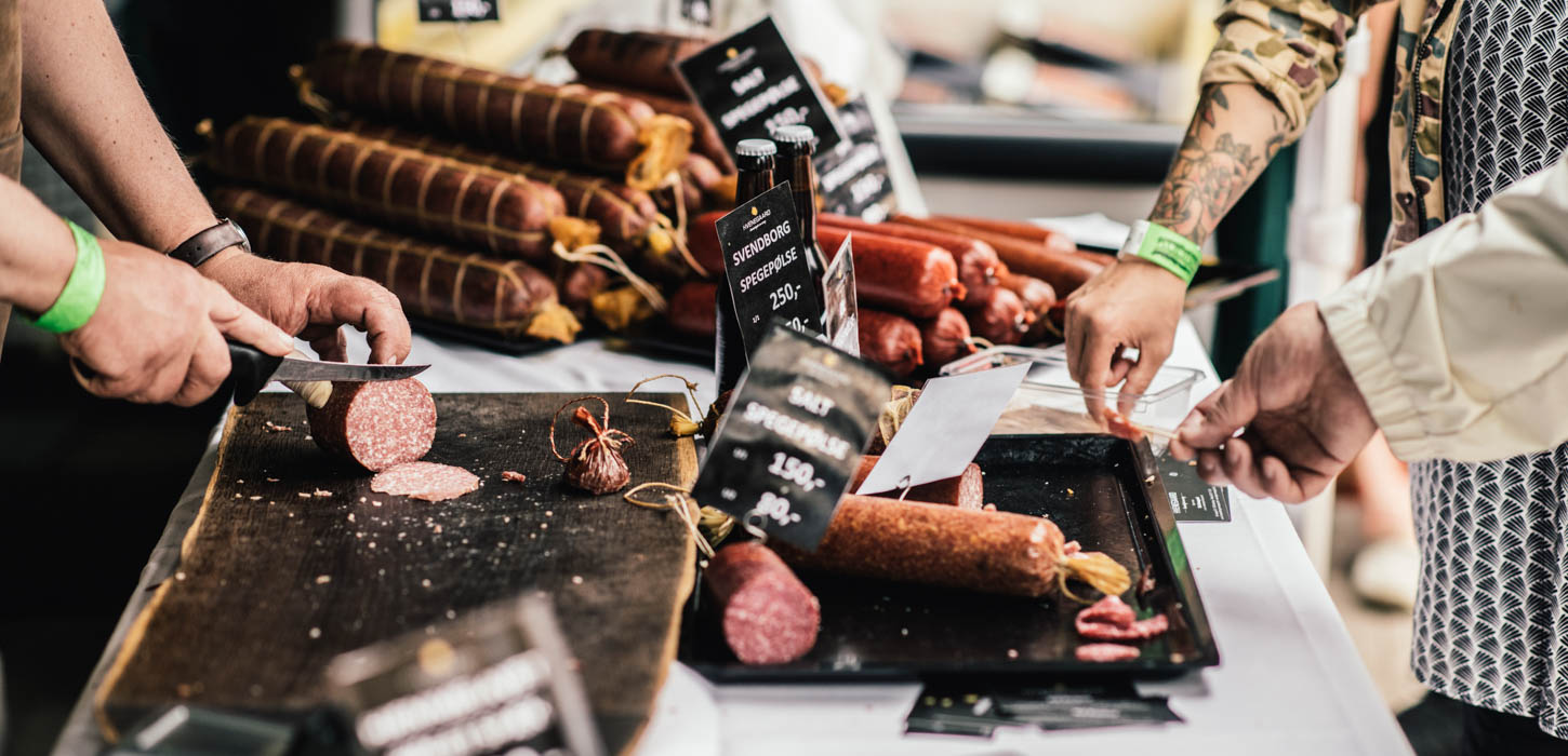 Et bord af pølser med prisskilte - nogle af dem er ved at blive skåret i skiver