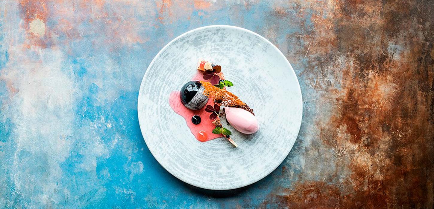 Gourmetdessert smukt anrettet set oppefra på rustikt bord.