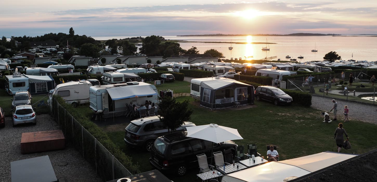 Solnedgang over havet og en fyldt campingplads.