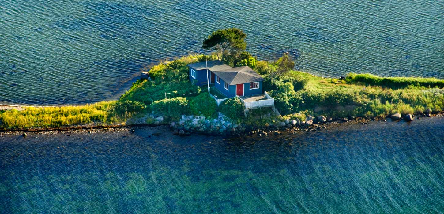 Lille ø med blåt sommerhus med blåt vand til alle sider