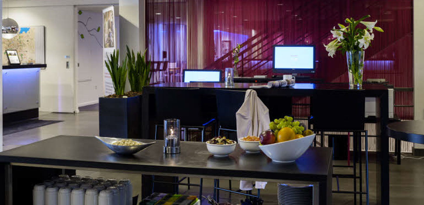 Et hotel set indefra med reception samt borde med frugt og lignende.