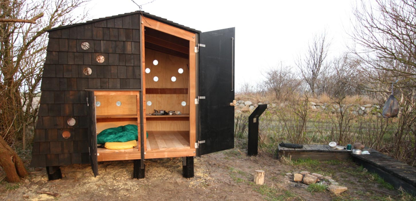 Shelter med træinteriør og en lille plads foran.