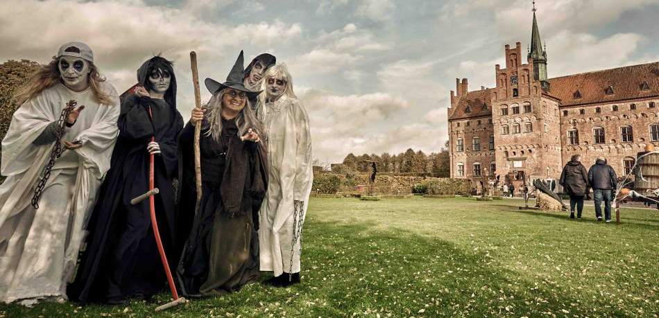 Til venstre står fem børn udklædt som spøgelser, dæmoner og hekse. Til højre går et par foran Egeskov slot.