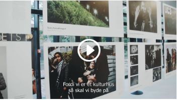 En masse billeder hænger på et glasparti. Der er et videoikon i midten af billedet. 