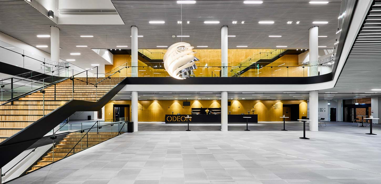 Stor, tom sal i Odeon, hvor man kan se, etagen overover også. Der er trapper i venstre og højre side af salen og en stor, rund lampe hænger ned i midten af billedet og oplyser salen.