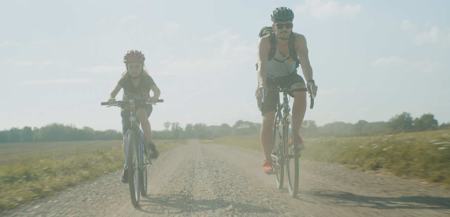 Far og søn på gravel bikes på støvet grusvej.