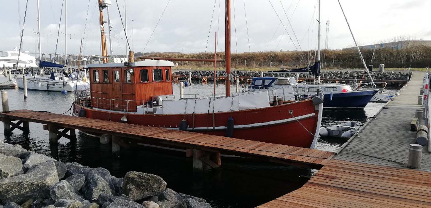 Stor rød sejlbåd ligger til ved havnen. 
