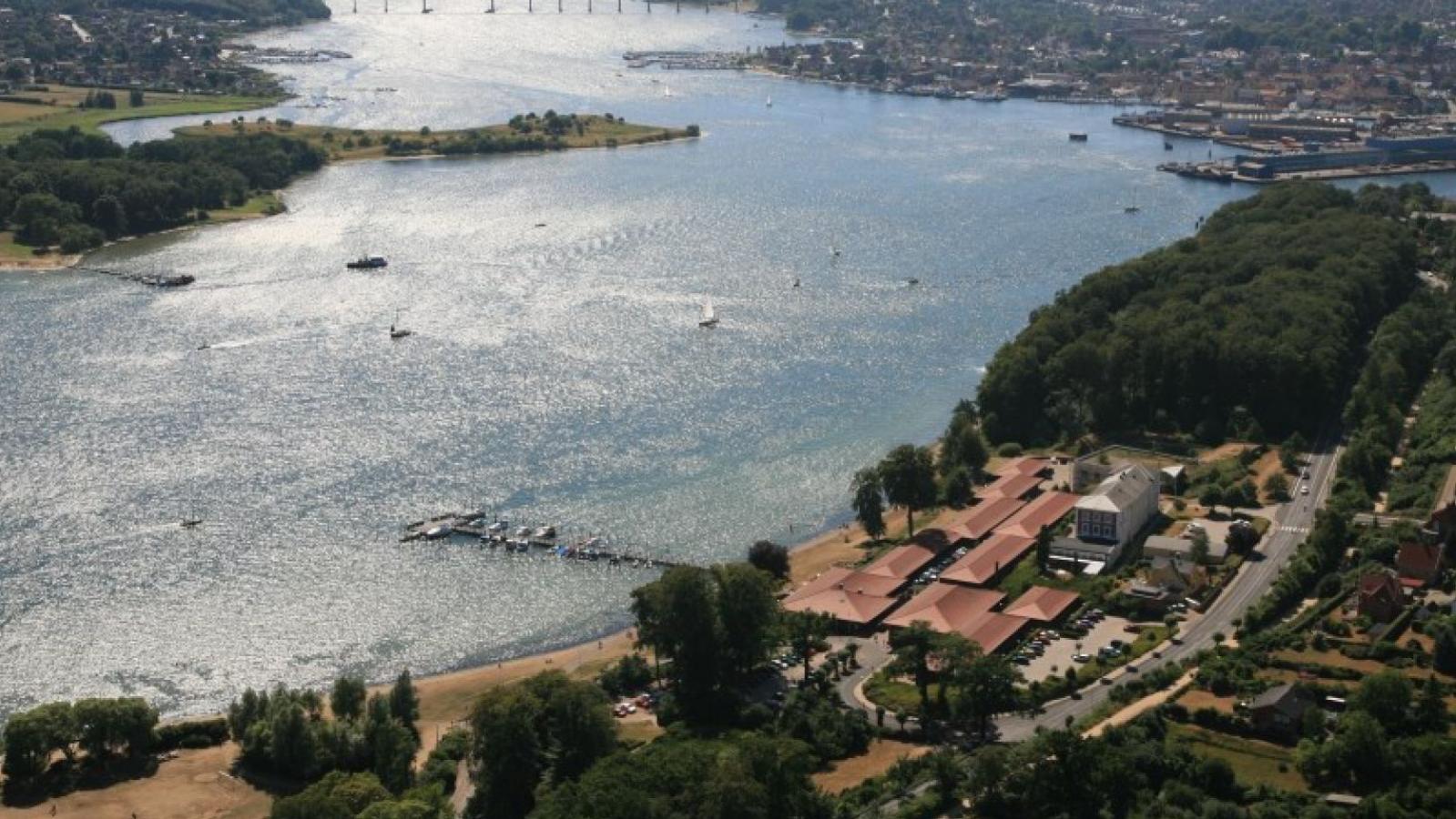 Dronebillede af Hotel Christiansminde. Man kan se vandet og rundt om hotellets røde tage er der skov. 