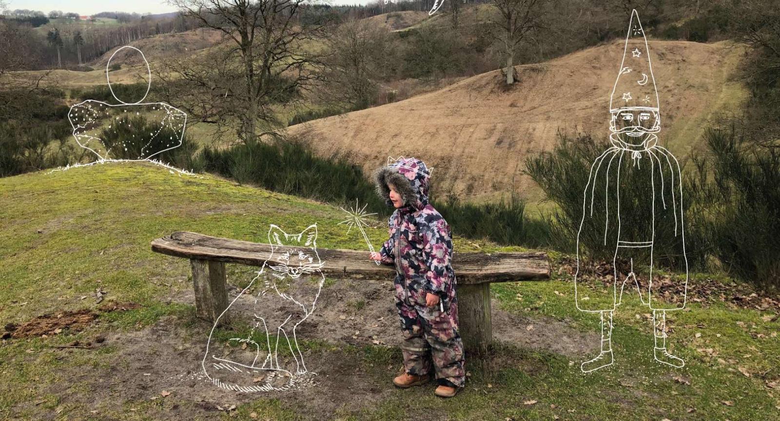 Et barn i flyverdragt står ved siden af en bænk omgivet af marker. Illustrationer af en troldmand og en ulv.
