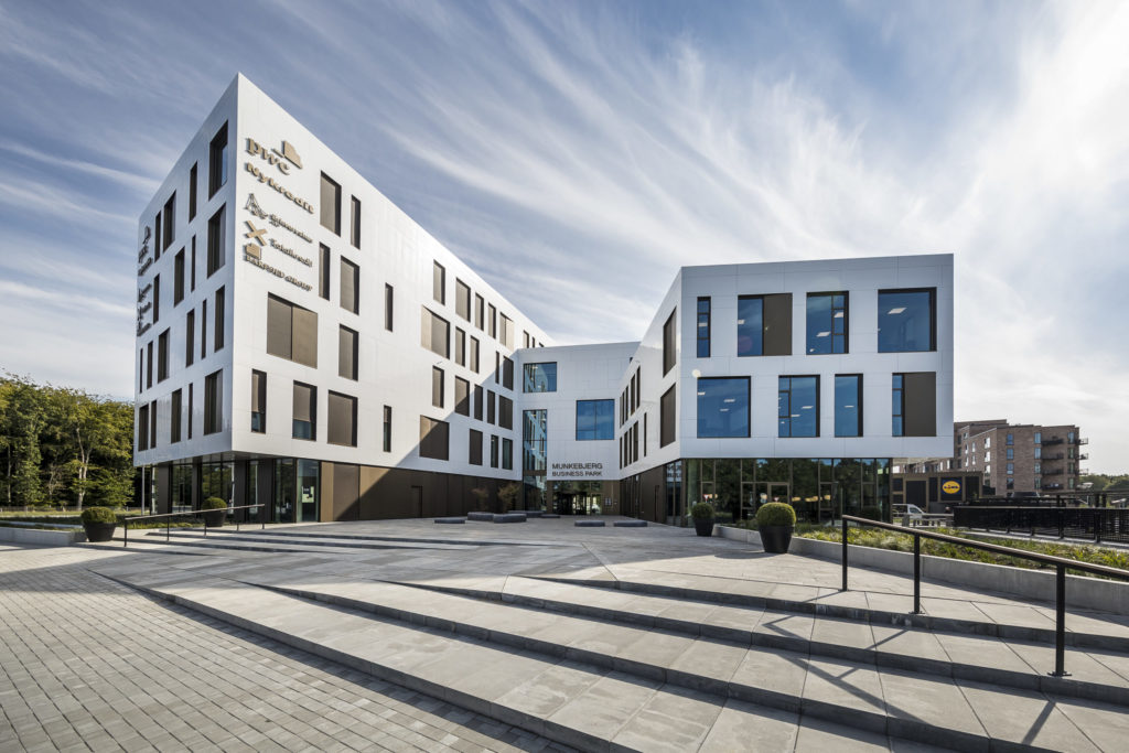 Stor, hvid erhvervspark med mange store vinduer og flade trapper op til indgangen.