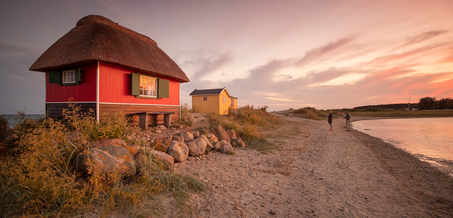 Et rødt og et gult badehus i pink solnedgang ved Eriks Hale ved Marstal, Ærø.
