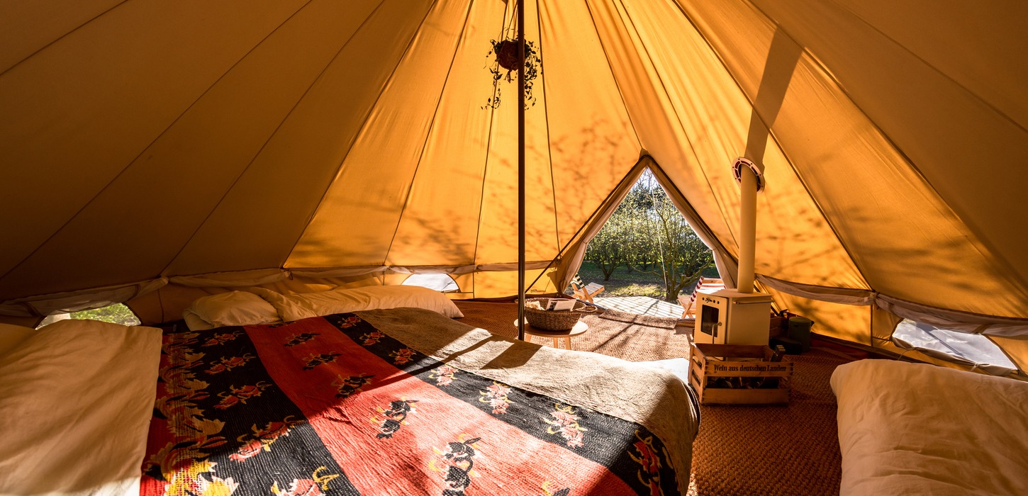 Hyggeligt glampingtelt set indefra i et varmt lys.