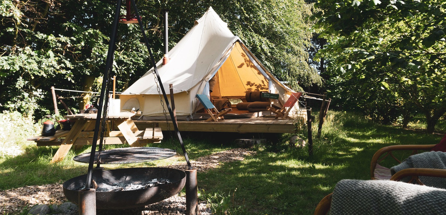Glamping telt står midt i grønne og hyggelige omgivelser.
