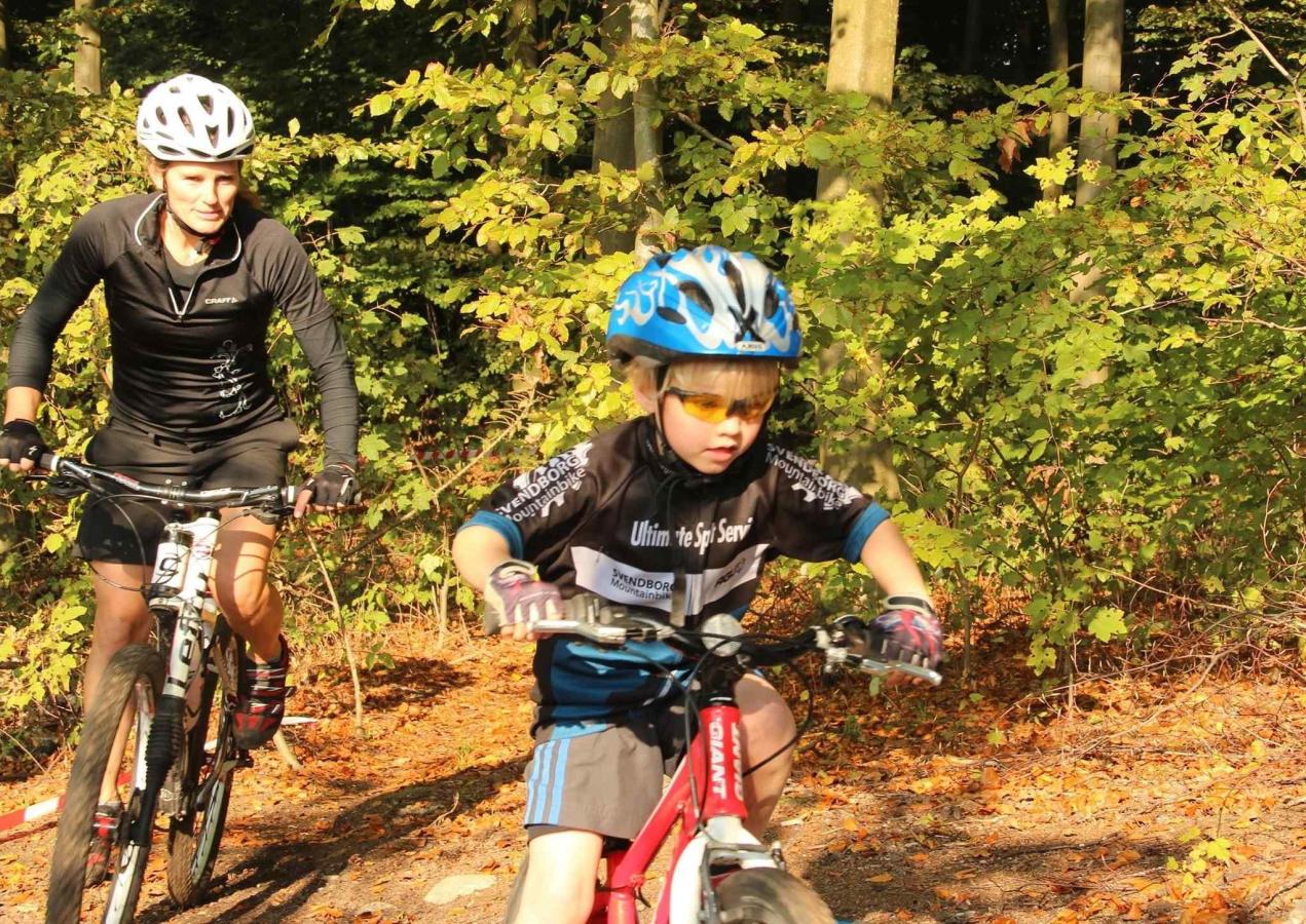 Kvinde og barn på mountainbike i skovterræn.