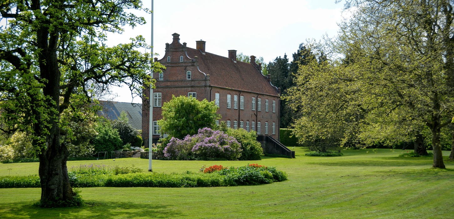 Stor, flot og velholdt have med et gods i baggrunden.