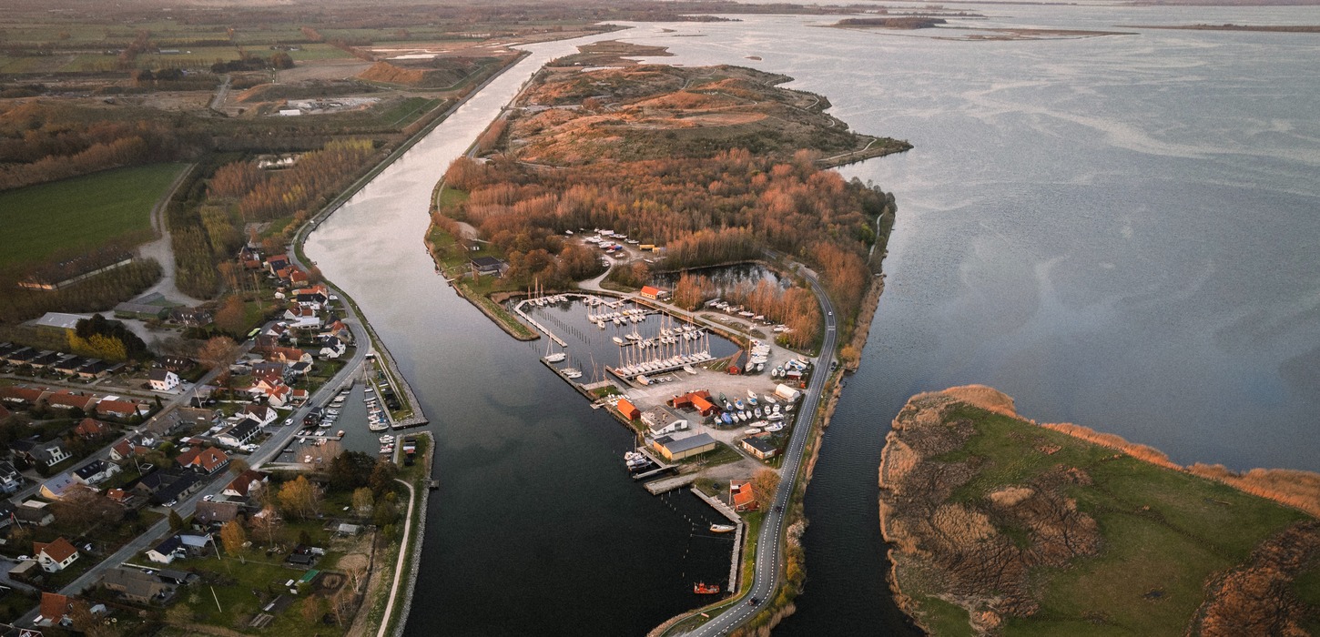 Lille ø i varme efterårsfarver set foroven, fotograferet med drone. 