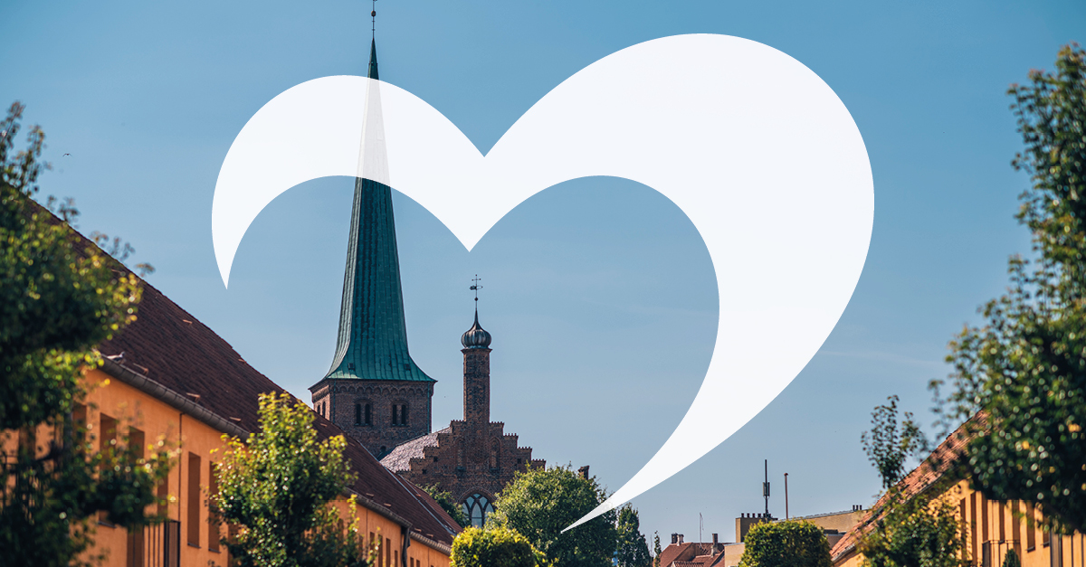 Skyline over en hyggelig, orange købstad med bomærke over.