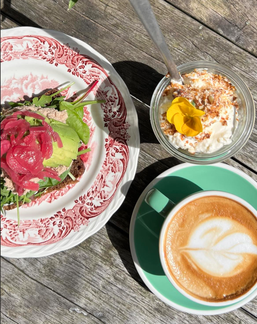 Nærbillede af kaffe, kage og avokadomad stående på træbord