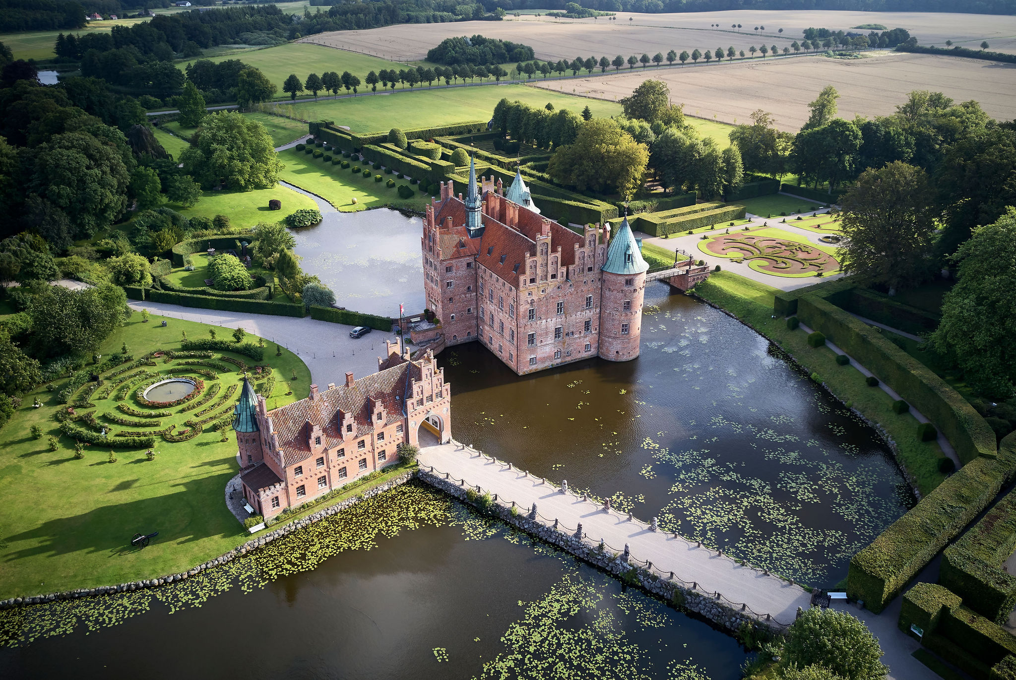 Dronefoto af Egeskov Slot med voldgrav og grønt omkring