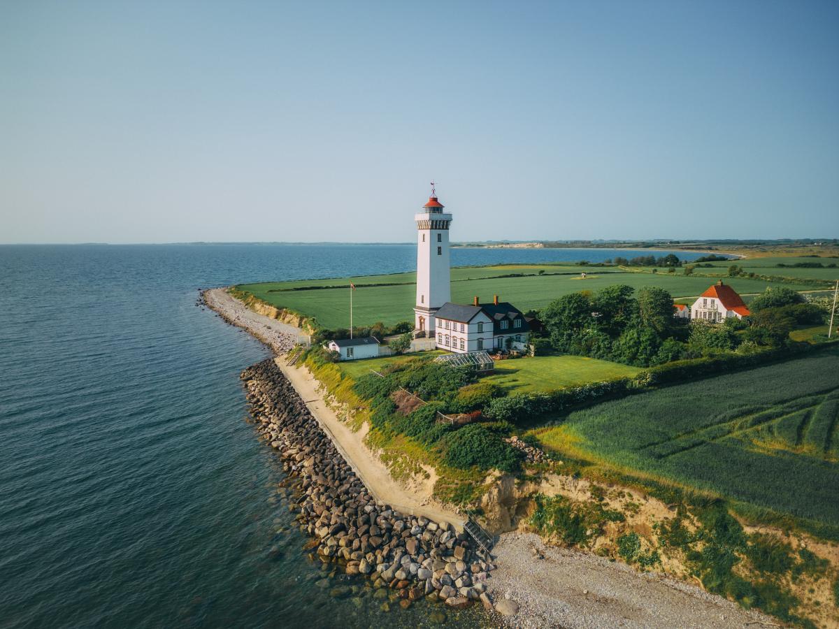 Hvidt fyr ud til vandet i grønne omgivelser