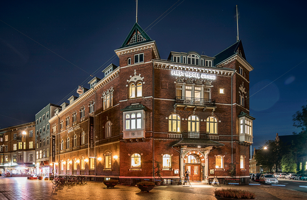 En gammel murstensbygning oplyst af aftenbelysning 