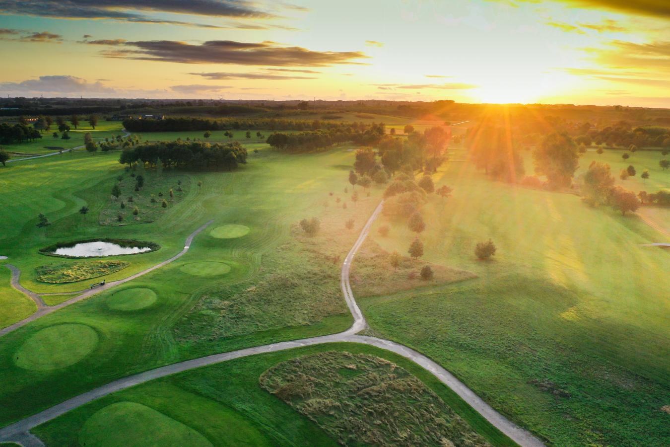 Odense Eventyr Golf set oppefra med solopgang i baggrunden