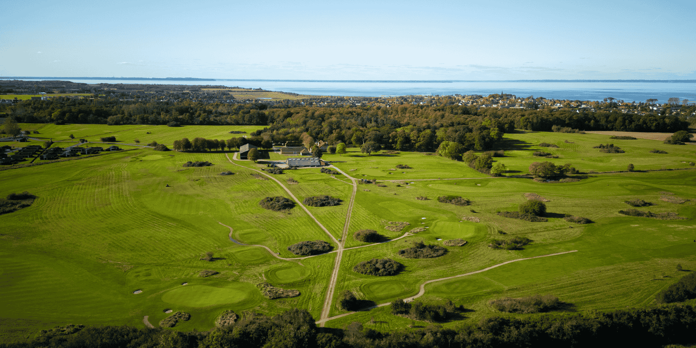 Dronefoto af grøn golfbane med træer og stier