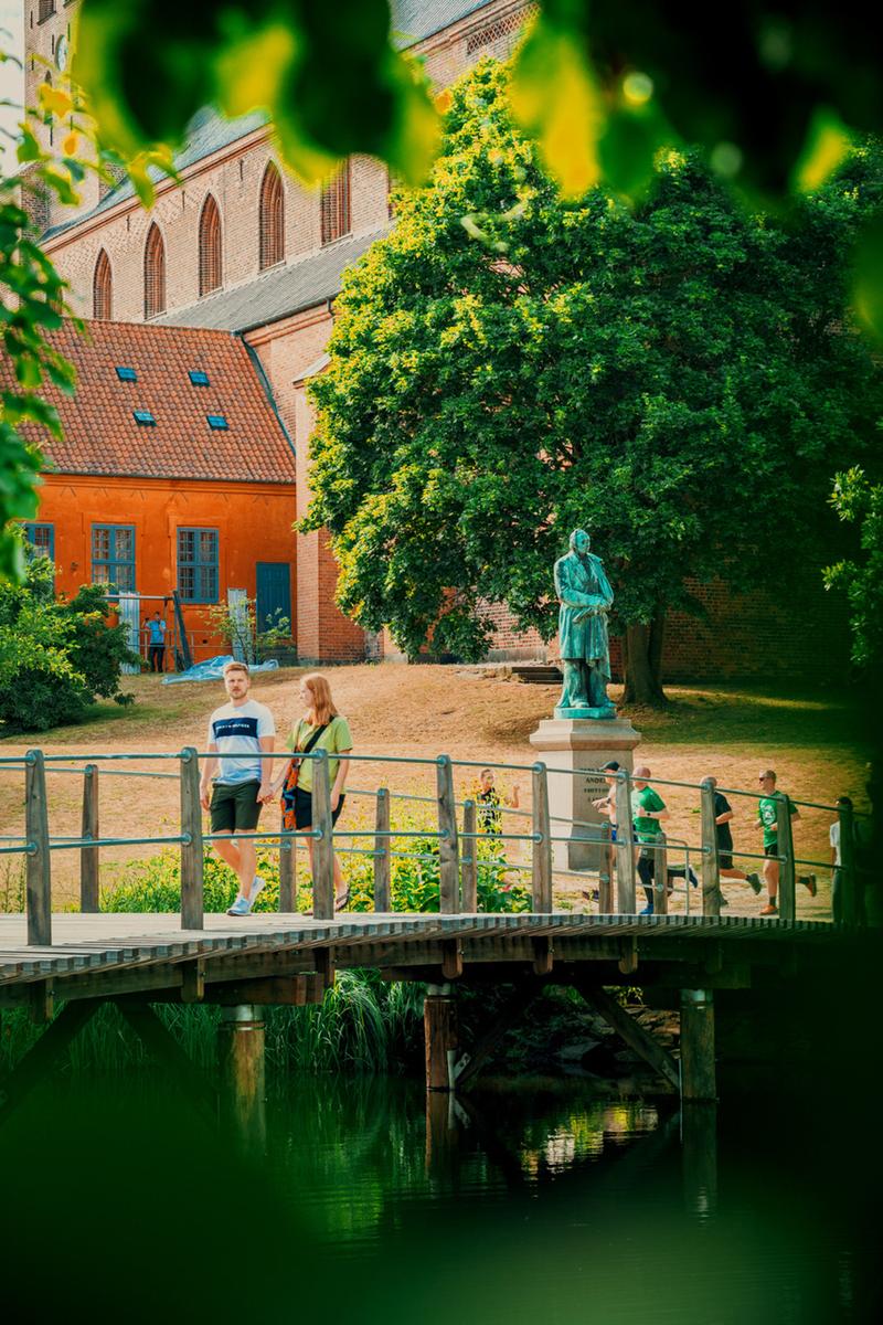 En bro over Odense Å med en skulptur af H. C. Andersen i baggrunden