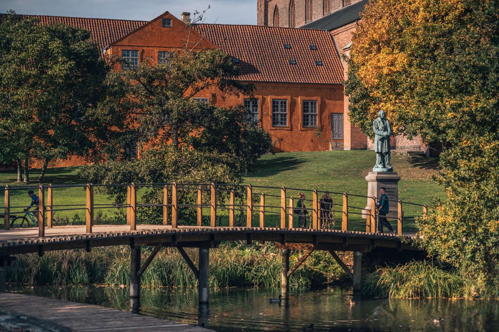 En bro over Odense Å med en skulptur af H. C. Andersen i baggrunden