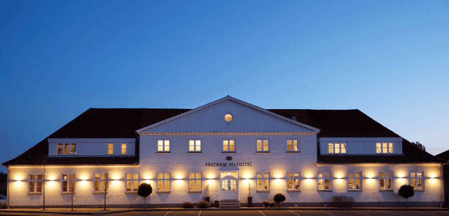 En lang hvid bygning med oplyste vinduer