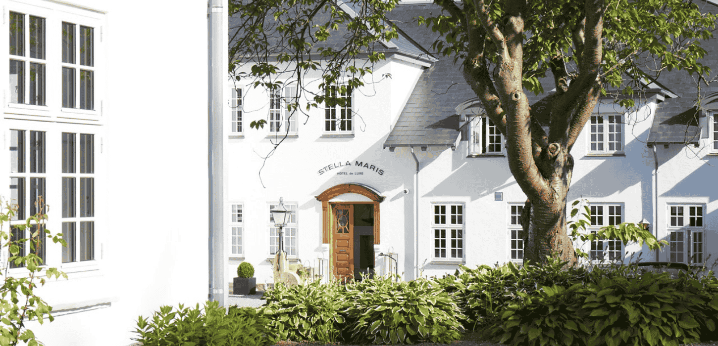 Hvid facade med massiv trædør og et gammelt træ foran