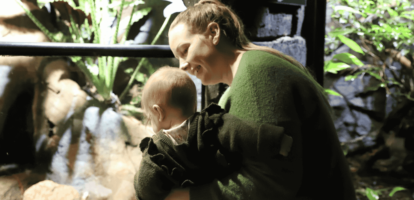 En mor holder sit barn i armene foran en glasvæg 