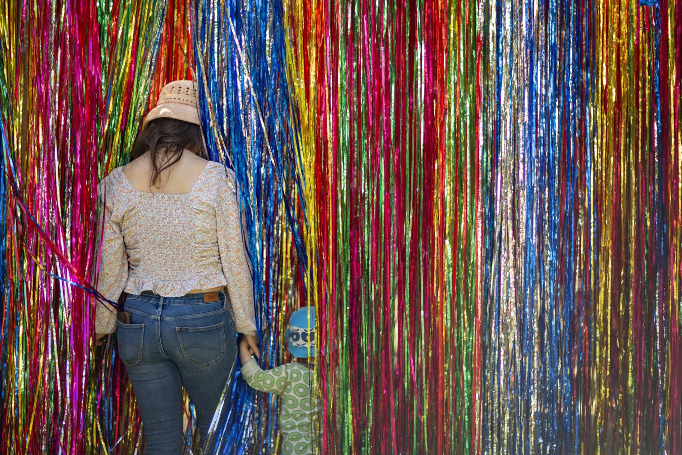 Kvinde med barn i hånden på vej ind gennem glimmer gardin.