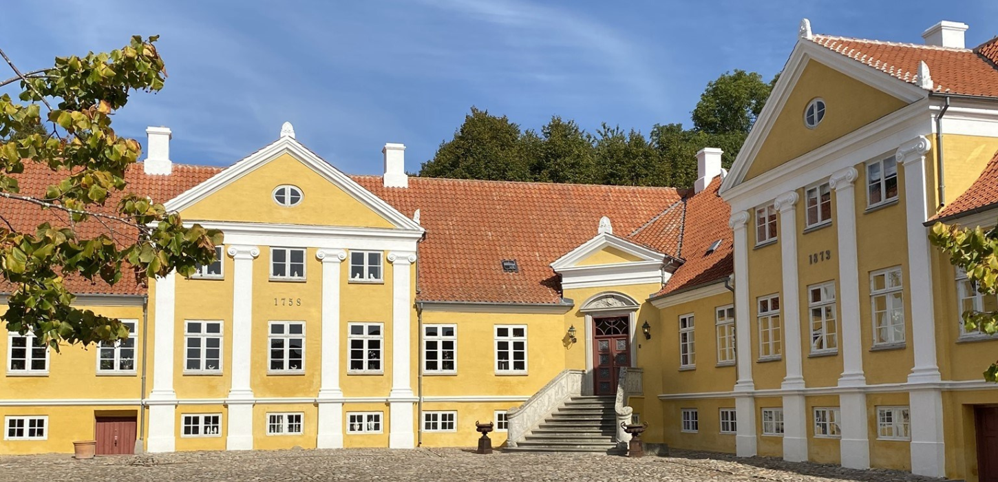 Broløkke Herregård med sol på den gule facade