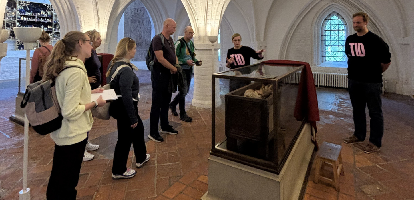 Besøgende og to rundvisere fra TID foran glasmontre.