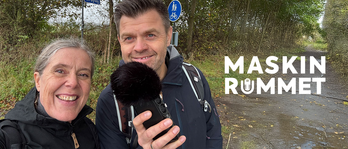 To personer i naturen, den ene holder en mikrofon. På billedet ses teksten Maskinrummet.