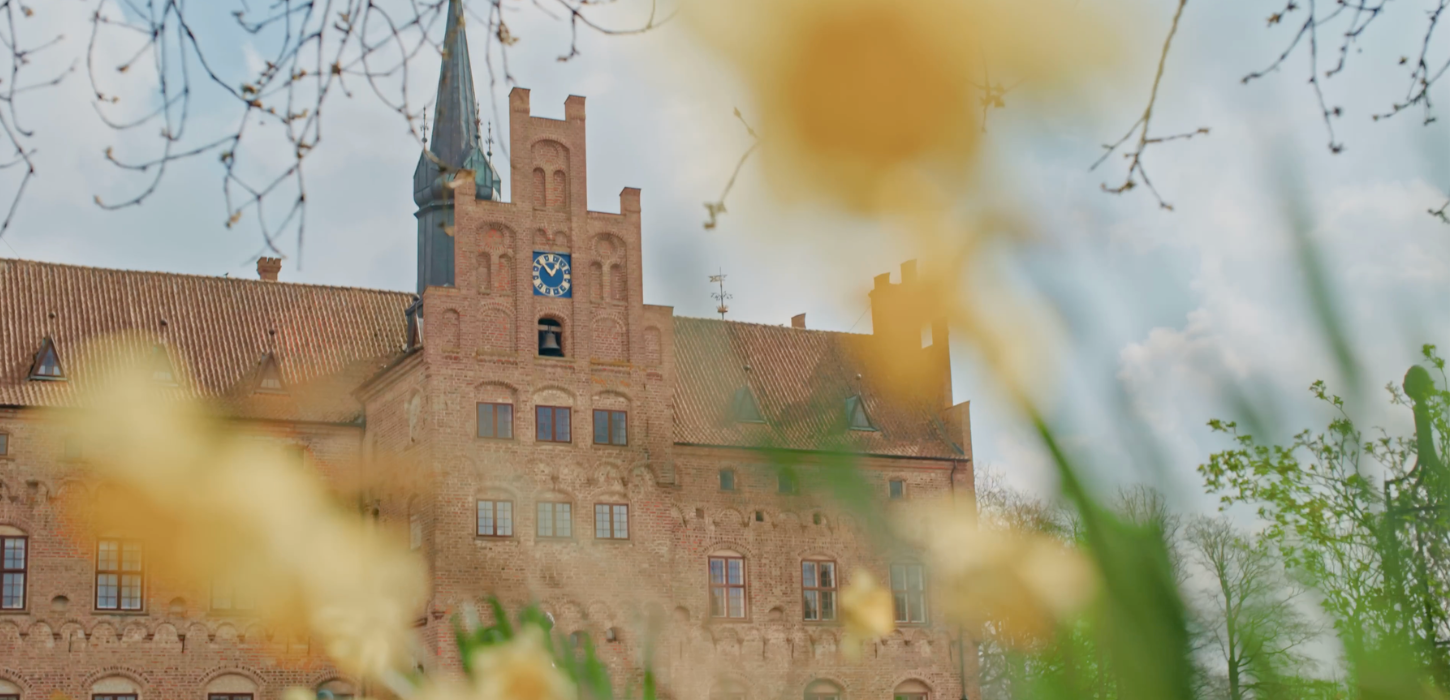 Egeskovs facade med påskeliljer i forgrunden