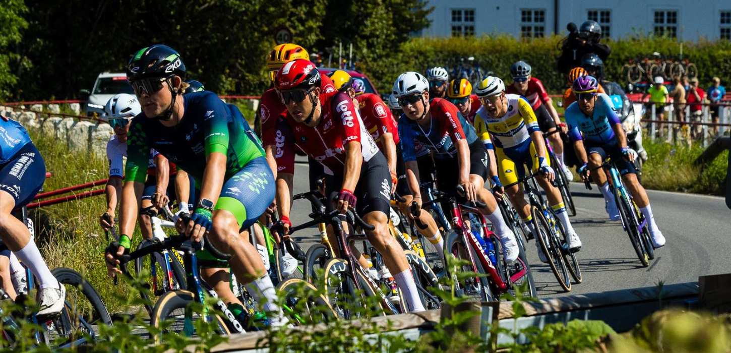 Cykelryttere på vej rundt i sving med tilskuere i baggrunden